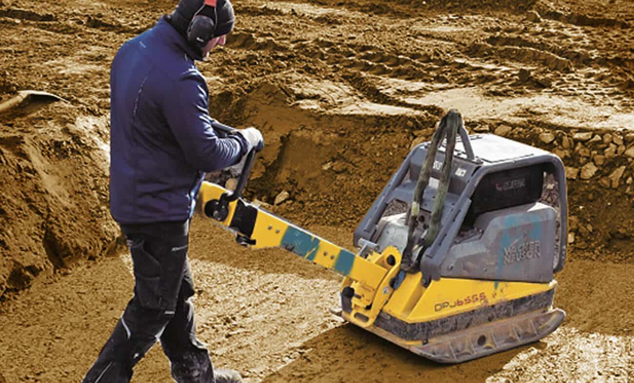 obrero trabajando con compactadora para nivelación de tierras